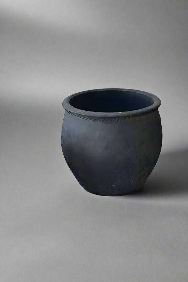 Dark gray clay pots on a concrete floor with a white wall background